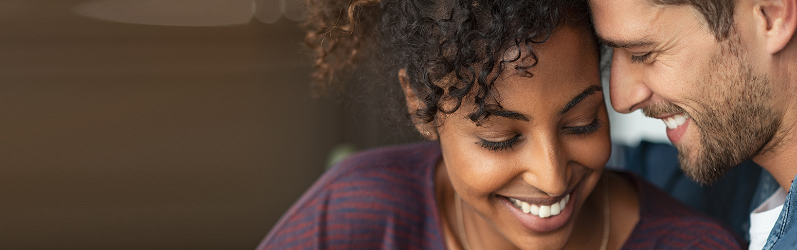 Portrait of attractive couple embracing each other. Closeup loving multiethnic couple embracing and kissing. Closeup face of cheerful boyfriend and african girl cuddling in love at home.